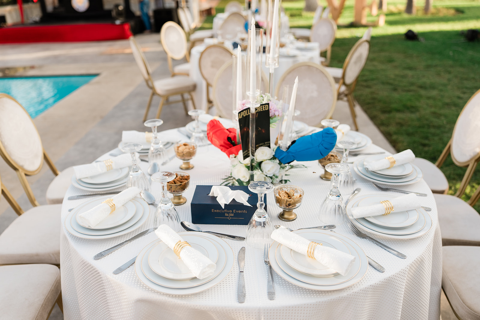 Table d'honneur dressée en extérieur avec chandeliers, bougies et compositions florales blanches